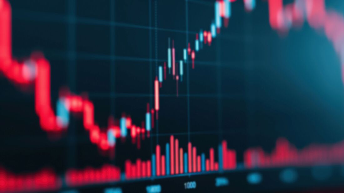 A close-up of a digital stock market chart showing bar graphs and line graphs in red, representing economic data and financial analysis.