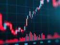 A close-up of a digital stock market chart showing bar graphs and line graphs in red, representing economic data and financial analysis.