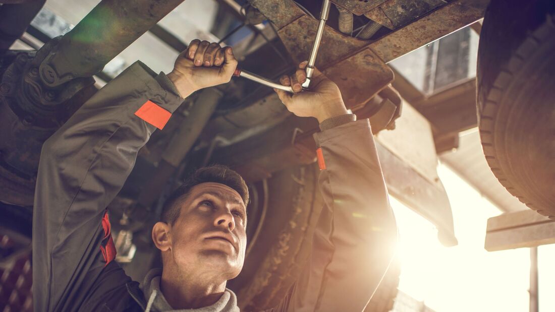 Auto mechanic repairing a chassis of a truck.