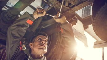 Auto mechanic repairing a chassis of a truck.