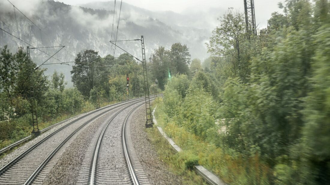 Blick auf eine zweigleisige, elektrifizierte Bahnstrecke, die durch eine neblige, bewaldete Landschaft führt. Korridorsanierungen zwingen Güterzüge teilweise zu langen Umwegen.
