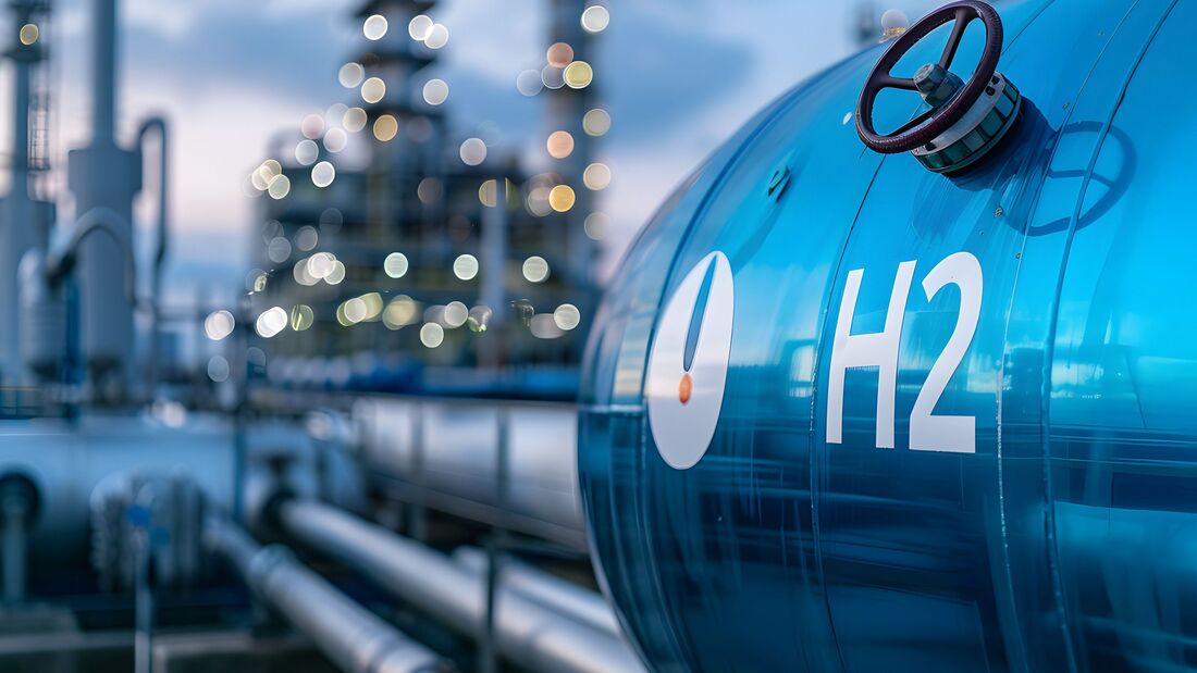Close up of an industrial "H2" fuel storage tank with a hydrogen power plant background symbolizing the transition to net zero emissions by 2050