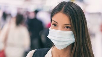 Coronavirus corona virus Asian woman wearing flu mask walking on work commute in public space transport train station or airport panoramic banner.