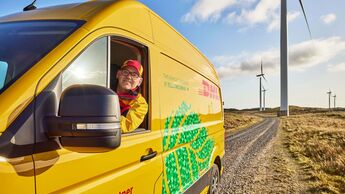 DHL-Transporter vor Windrädern. Der Logistikkonzern baut sein weltweites Netzwerk für Batterie- und Energielogistik aus.