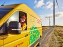 DHL-Transporter vor Windrädern. Der Logistikkonzern baut sein weltweites Netzwerk für Batterie- und Energielogistik aus.
