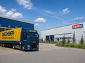 Dachser-Lkw vor einem Logistikzentrum neben einem Tesa-Gebäude als Symbol für den Wechsel der europäischen Lagerlogistik.