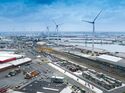 Der Portalkran am AZT-Terminal, ausgestattet für den intermodalen Containerumschlag, mit Windrädern im Hintergrund.