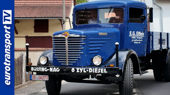 Der restaurierte Büssing 5000 fährt mit zwei Insassen durch eine Ortschaft. Der historische Lastwagen präsentiert sich nach der vollständigen Restaurierung in seinem ursprünglichen Erscheinungsbild. Links ist das eurotransportTV-Logo zu sehen.