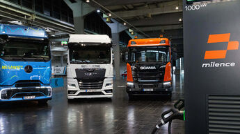 Drei Elektro-Lkw von Daimler Truck, MAN und Scania an einer Milence-Ladestation bei der MCS-Demonstration auf der IAA Transportation 2026.