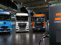 Drei Elektro-Lkw von Daimler Truck, MAN und Scania an einer Milence-Ladestation bei der MCS-Demonstration auf der IAA Transportation 2026.