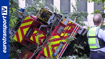 Ein Feuerwehrfahrzeug liegt verunglückt im Grünen, davor steht ein Polizist – oben rechts steht in rotem Kasten der Text „Trainieren, bevor’s kracht!“. Links ist senkrecht das eurotransportTV-Logo eingeblendet.