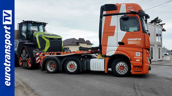 Ein Mercedes-Benz Actros von Fehrenkötter Transport biegt mit einem Claas XERION auf einem Tiefbettauflieger ab. Links ist das eurotransportTV-Logo zu sehen.