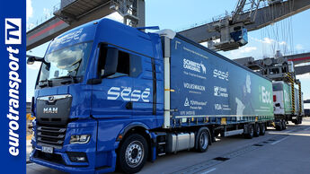 Ein blauer MAN-Lkw mit EcoDuo-Aufliegern von Schmitz Cargobull steht im MegaHub Terminal Lehrte; links im Bild ist das eurotransportTV-Logo sichtbar.