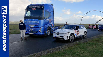 Ein blauer Volvo FH Electric und ein weißer Renault Megane E-Tech stehen auf einer Straße, mehrere Menschen drumherum. Links ist das eurotransportTV-Logo sichtbar.