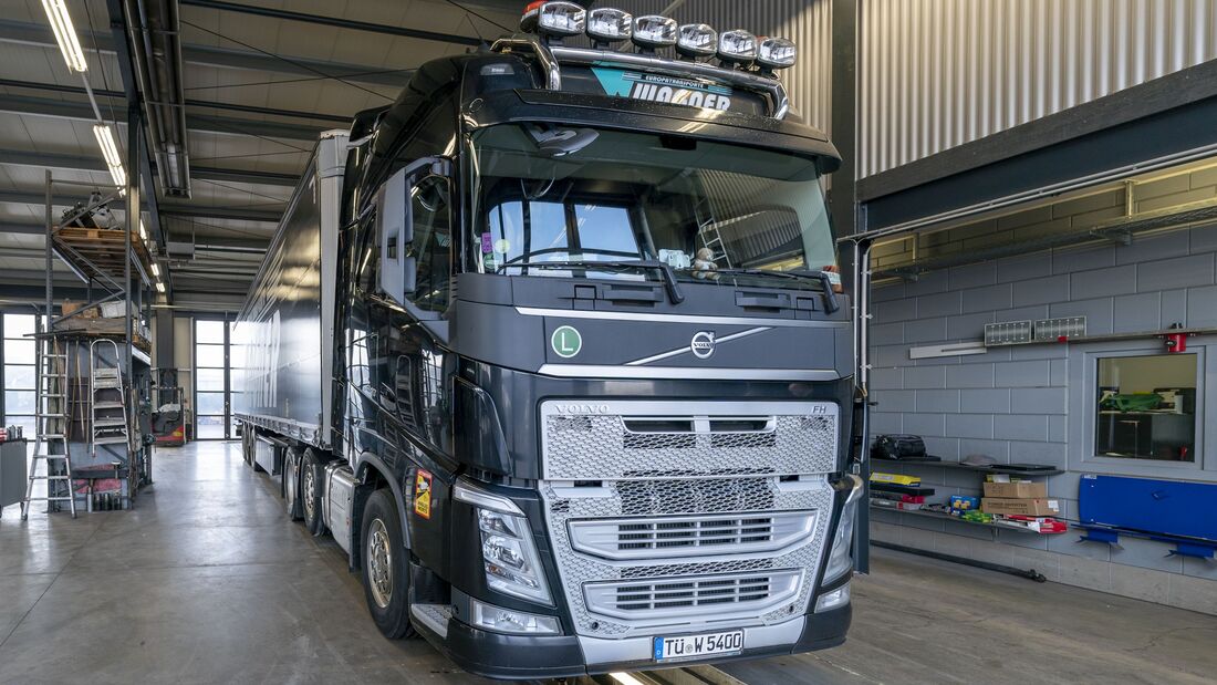 Ein grauer Lkw fährt in eine große Werkstatthalle.