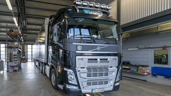 Ein grauer Lkw fährt in eine große Werkstatthalle.