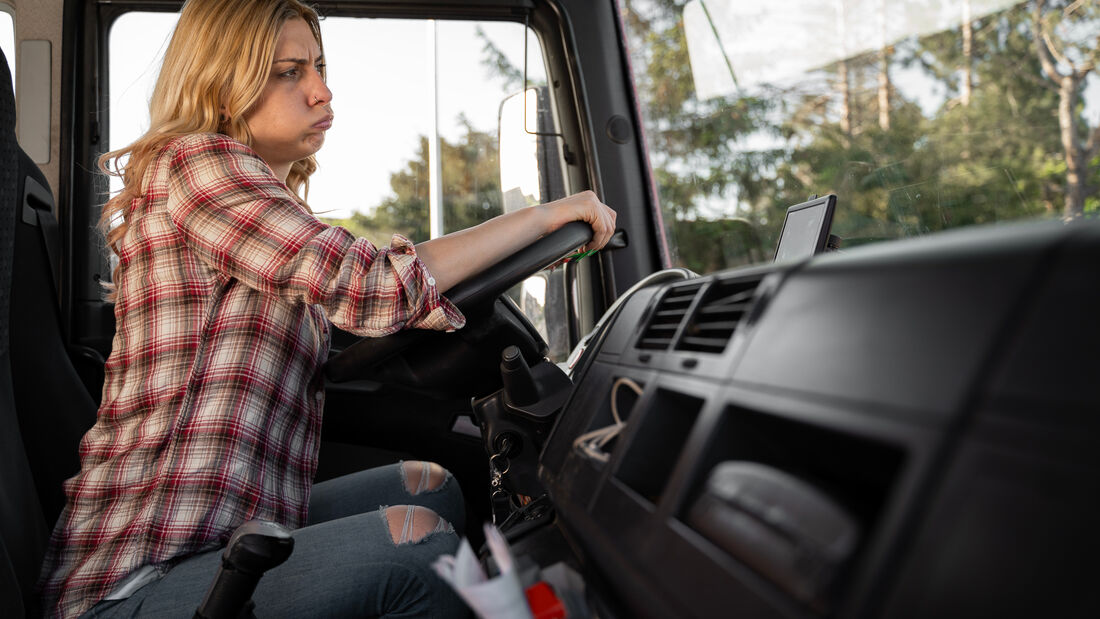 Frustrierte junge Lkw-Fahrerin atmet aus und runzelt die Stirn.