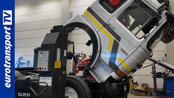 Gekippte Kabine eines restaurierten MAN F8 in der Werkstatt von Stratmann Fahrzeugtechnik, Mechaniker arbeitet am Fahrgestell, links das eurotransportTV-Logo.