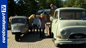Historische Kleintransporter bei einem Oldtimer-Treffen in Lohne: Zwei Männer tragen Säcke zwischen klassischen Nutzfahrzeugen aus der Wirtschaftswunderzeit. Im Vordergrund steht ein heller Kumer Diesel Transporter, links ein kleiner Dreirad-Transporter. Das eurotransportTV-Logo befindet sich am linken Bildrand.