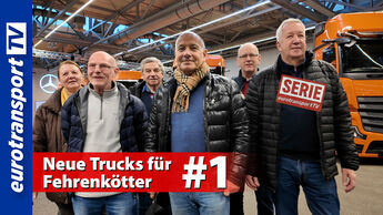 Joachim Fehrenkötter steht mit seinem Team vor neuen Actros-Lkw in der Auslieferungshalle bei Mercedes in Wörth. Links im Bild ist das eurotransportTV-Logo sichtbar. Zu sehen ist auch der Serienstempel und die Schrifteinblendung: "Neue Trucks für Fehrenkötter #1". 
