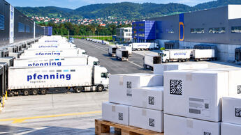 KI-Montage auf Basis eines Pfenning-Fotos: Pharma-Versandkartons mit Data-Matrix-Codes vor einem Logistikzentrum der Pfenning-Gruppe.