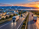 KI-generierte Darstellung einer vernetzten Transportlogistik mit Lkw auf einer Autobahn, Logistikzentren und leuchtenden digitalen Verbindungslinien vor einer abendlichen Landschaft.