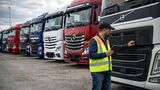 Käufer prüft gebrauchten Lkw auf Händlerhof mit mehreren abgestellten Nutzfahrzeugen