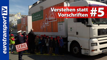 Kindergruppe mit roten Kappen vor einem Lkw-Aufbau mit Verkehrswarnsymbolen, daneben ein Polizist und Erwachsene in einer Verkehrssicherheitsaktion. Sichtbar sind das eurotransportTV-Logo, der Serienstempel sowie die Schrifteinblendung „Verstehen statt Vorschriften #5“.