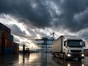 Lkw im Industriehafen unter dunklem Himmel als Symbol für wirtschaftlichen Abschwung in der Logistik