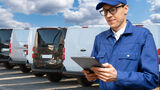 Manager,With,A,Digital,Tablet,On,The,Background,Of,Vans.