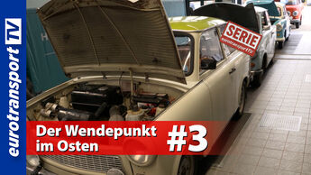 Mehrere Trabant-Fahrzeuge mit geöffneten Motorhauben in einer Halle, aufgenommen aus seitlicher Perspektive. Sichtbar sind das eurotransportTV-Logo, der Serienstempel sowie die Schrifteinblendung „Der Wendepunkt im Osten #3“.