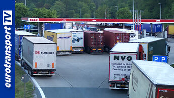 Mehrere dicht parkende Lkw auf einer überfüllten Rastanlage mit Tankstelle, enge Zufahrten und wenig Platz, eurotransportTV-Logo am linken Bildrand.