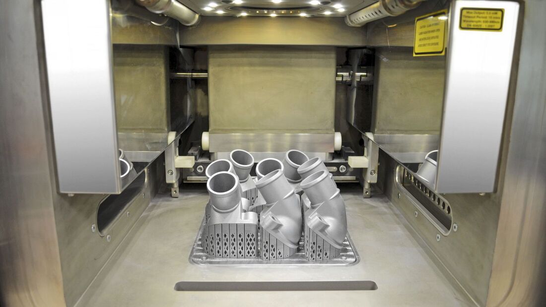Mercedes-Benz Lkw ist weltweit Technologieführer beim Einsatz von 3D-Druckteilen und produziert künftig auch komplexe metallische Ersatz- und Sonderbauteile in höchster Qualität. Der Blick in den Innenraum des 3D-Druckers zeigt die ersten gedruckten Thermostatabdeckungen, die noch mit der Bauplattform verbunden sind. Nach dem Entfernen von Plattform und stützender Struktur wird das abgesaugte, gesiebte und gereinigte Aluminium-Silizium- Metallpulver ökologisch der Wiederverwendung zugeführt. 

Mercedes-Benz Trucks is the worldwide technological leader in the use of 3D printed components, and will in future also produce complex metallic spare and special parts in first-class quality. The view into the interior of the 3D printer shows the first printed thermostat covers, which are still connected to the work platform. After removal of the platform and support structure, the aluminium/silicon metallic powder is removed by suction, sieved, cleaned and ecologically fed back into the recycling system.