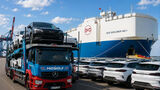 Mosolf-Autotransporter mit BYD-Fahrzeugen vor einem RoRo-Schiff und abgestellten BYD-Autos in einem Hafen.