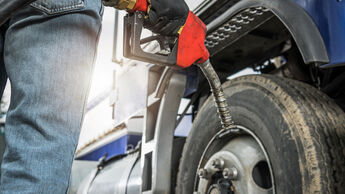NUR ZUM EINMALIGEN GEBRAUCH - Aged Semi Truck Driver About to Refuel His Tractor Truck Holding Diesel Pump Nozzle in His Hand. Heavy Duty Transportation and Fuel Shortage Concept.