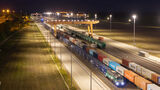 Nächtliche Luftaufnahme des Intermodalterminals East-West Gate im ungarischen Fényeslitke. Ein Containerzug steht unter einem großen gelben Portalkran. Auf den Gleisen und Umschlagflächen sind zahlreiche Container zu sehen, darunter mehrere von CMA CGM und Maersk.