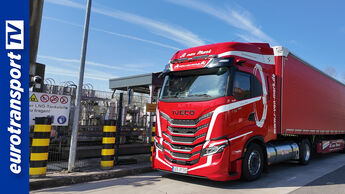 Roter IVECO S-WAY LNG-Sattelzug der Spedition van Mark steht an einer LNG-Tankstelle, links sind Zapfanlage, Warnschilder und Industrieanlagen sichtbar, im Hintergrund blauer Himmel; links im Bild ein vertikaler blauer Streifen mit eurotransportTV-Logo.