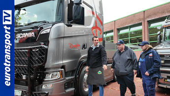 Scania-Lkw vor einer Werkstatt mit drei Personen, Vater Dirk Obermann, Sohn Nick Obermann und Bruno Dreßen, eurotransportTV-Logo links im Bild sichtbar.