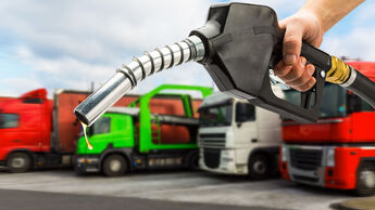 Zapfpistole in Hand im Hintergrund div. LKW